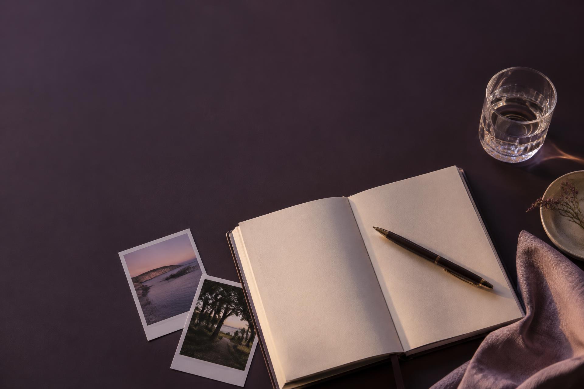 An open journal, a pen and photographs laid out for a quiet evening